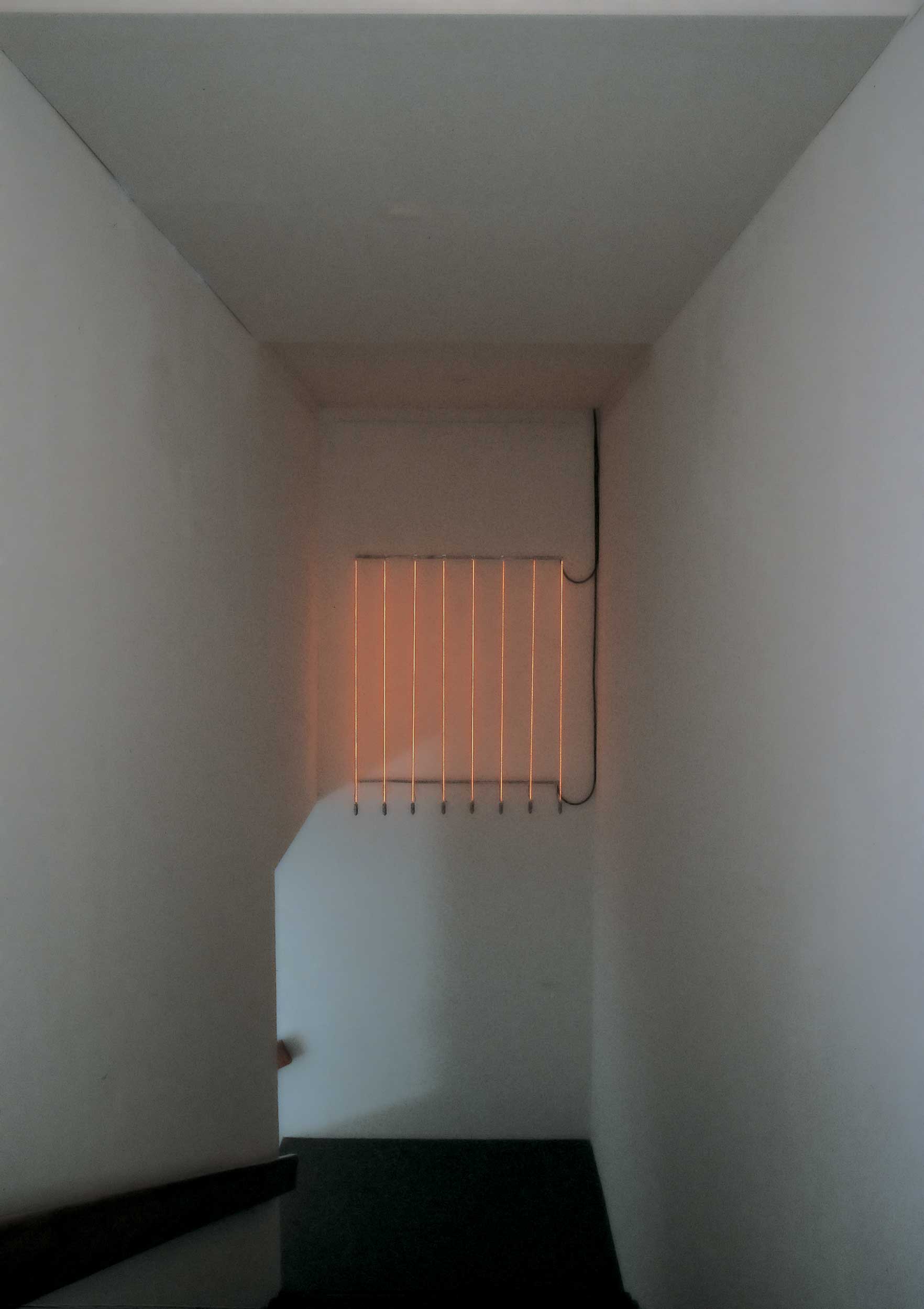 Glowing Wire Installation: front view of artwork hanging high on wall