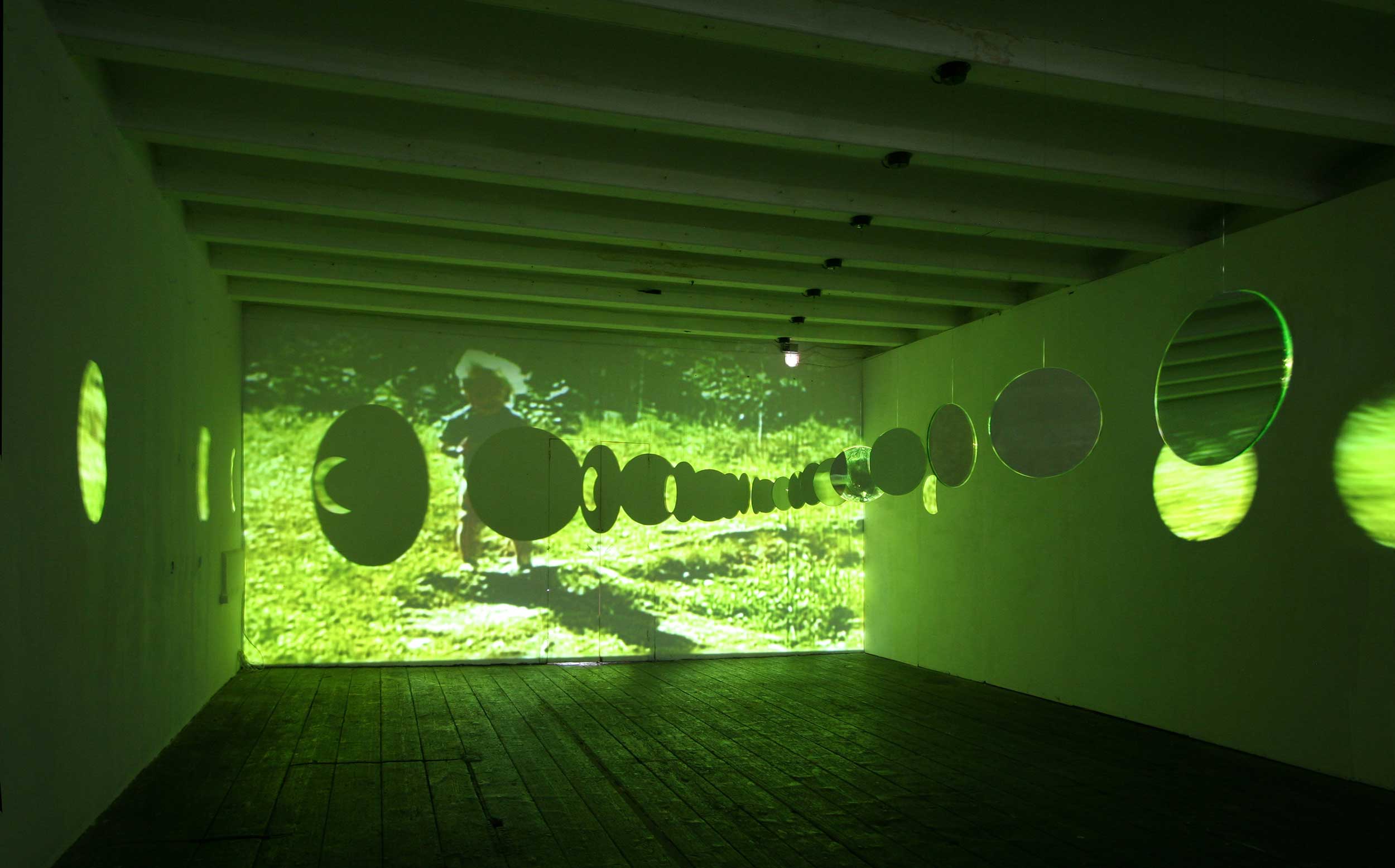 Memoria Fragmentada: exhibition space with video in background and hanging mirrors
