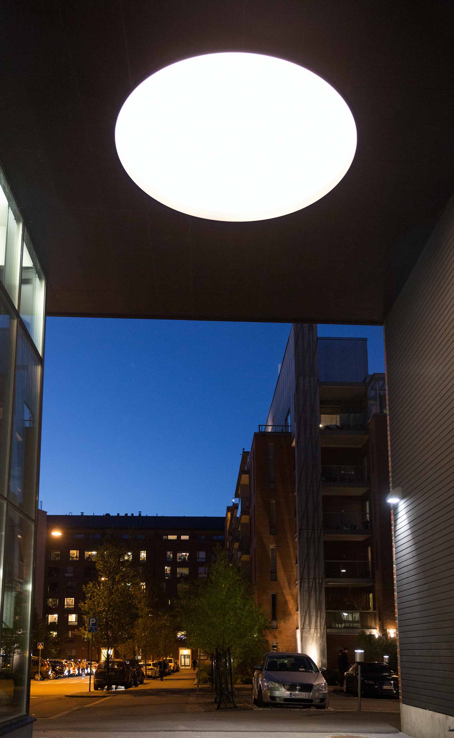 Tunnel with installation on ceiling and apartment buildings in the background during night