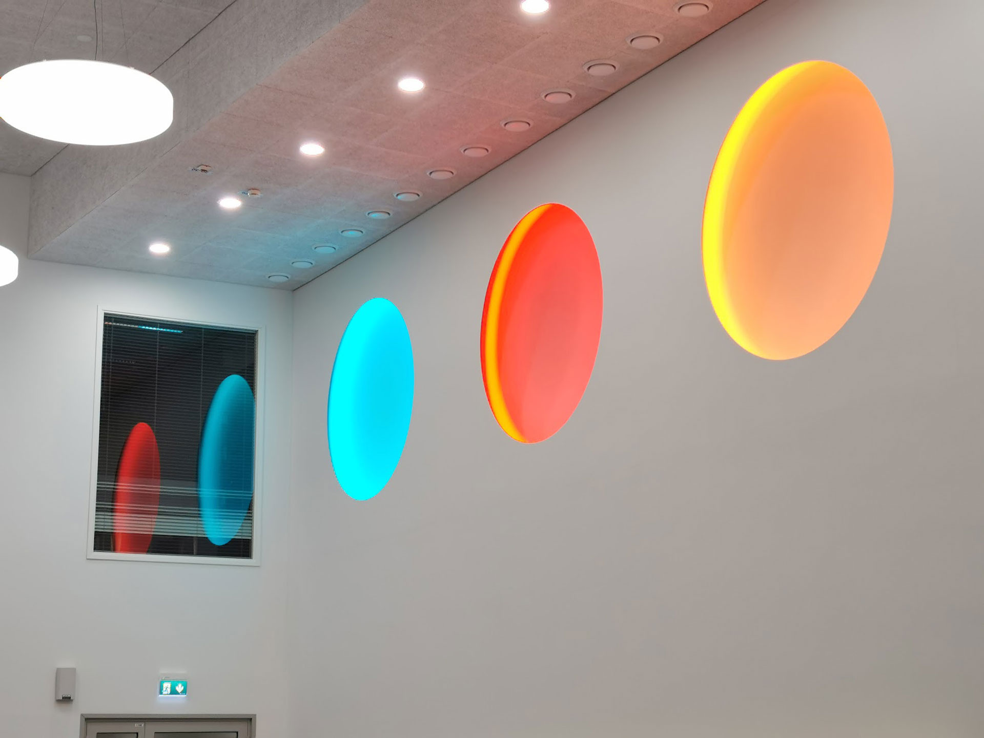 Close-up of installation from beneath lit in cyan, red and orange