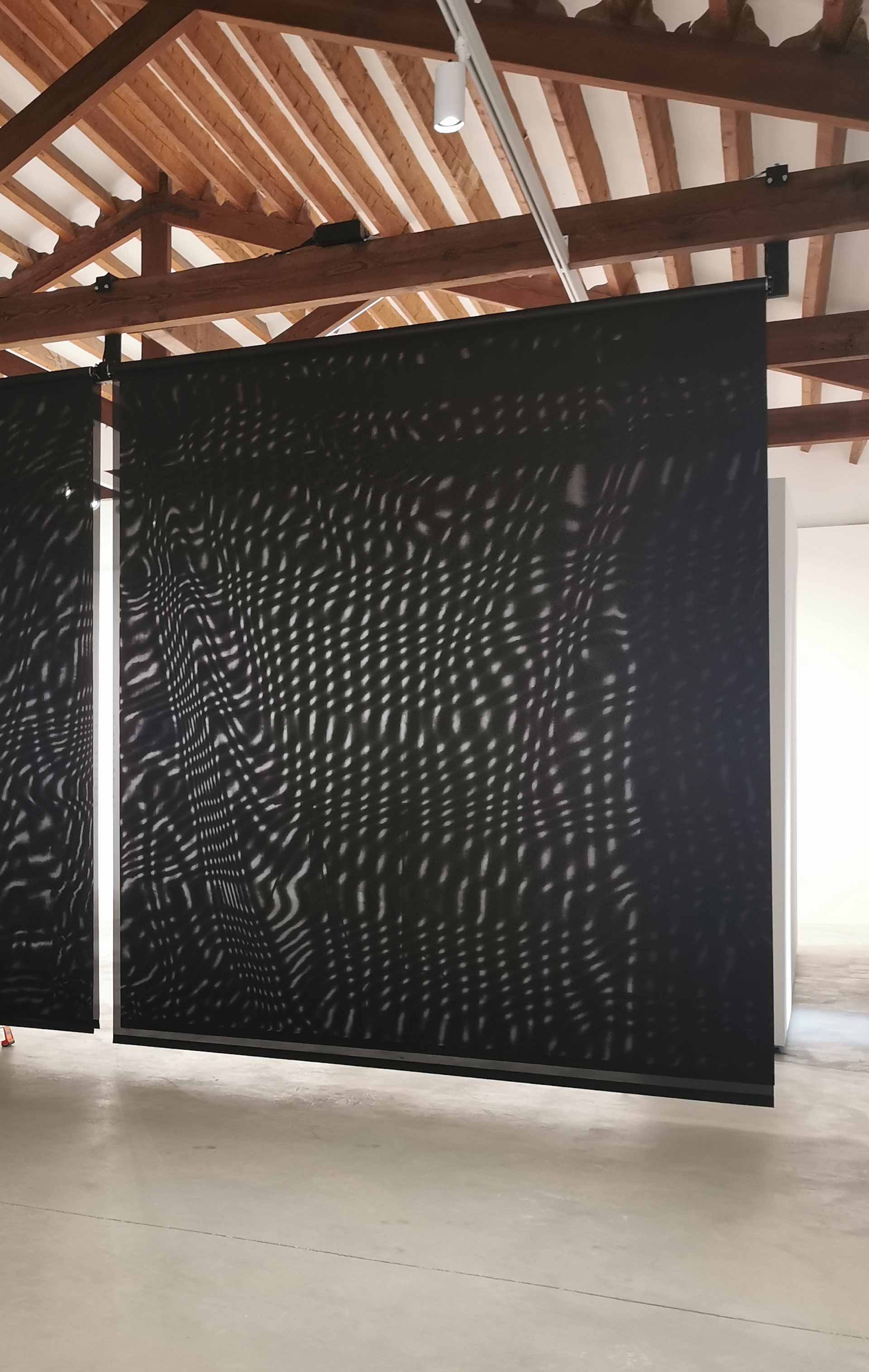 Blind Zone; black blinds hung from wooden beam on ceiling